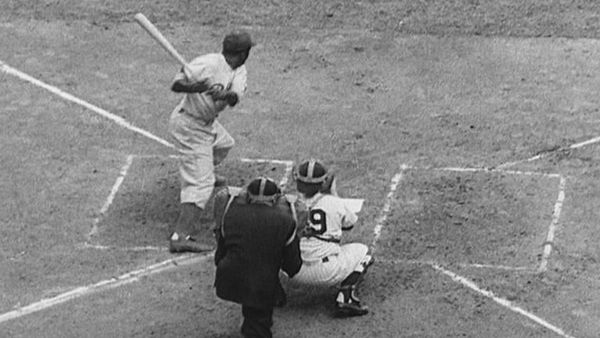 A black and white image of Jackie Robinson swinging a bat at home plate